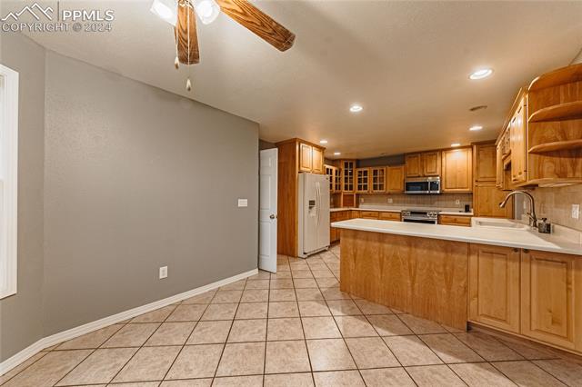 1027 County Road LL Fowler, CO 81039 - Photo 11 of 37 Kitchen featuring ceiling fan, tasteful backsplash, appliances with stainless steel finishes, sink, and kitchen peninsula