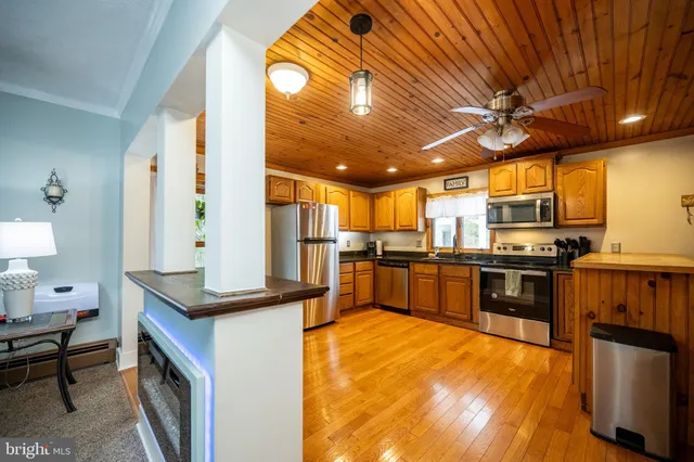 a large kitchen with stainless steel appliances granite countertop a stove a sink dishwasher a microwave oven with cabinets and wooden floor