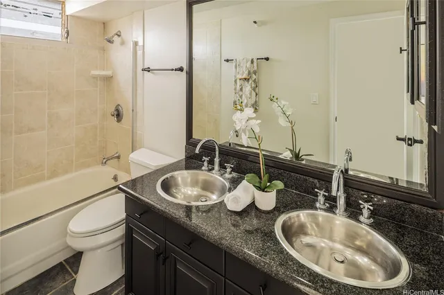 a bathroom with a granite countertop toilet sink and mirror