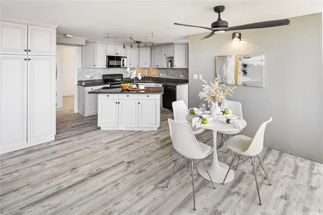 a kitchen with stainless steel appliances kitchen island granite countertop a table chairs and a refrigerator
