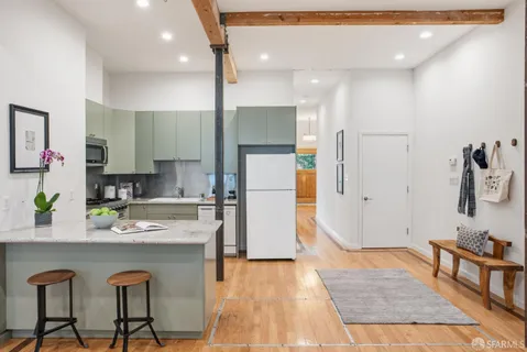 a kitchen with granite countertop a refrigerator a stove a sink and a dining table with wooden floor