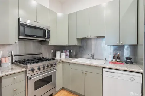 a kitchen with stainless steel appliances granite countertop grey cabinets a stove a sink and dishwasher