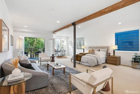 a spacious bedroom with a bed a couch and a large window