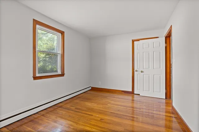 a view of an empty room with window and wooden floor