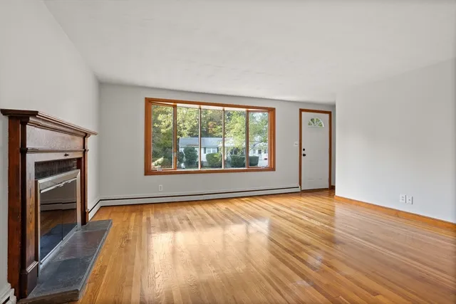 a view of an empty room with a window and wooden floor