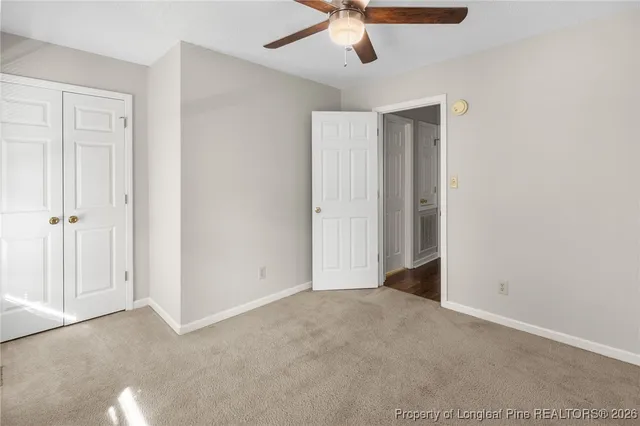 an empty room with a ceiling fan and carpet
