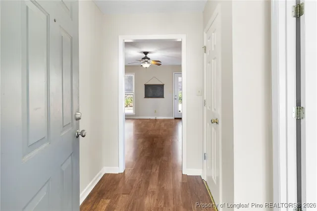 a view of a hallway with wooden floor and a bathroom