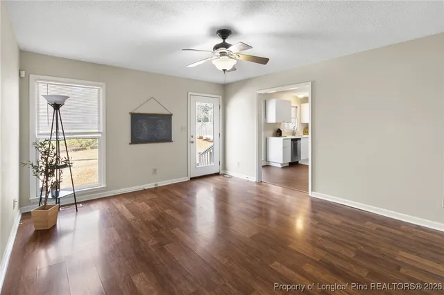 a view of an empty room with wooden floor and a window