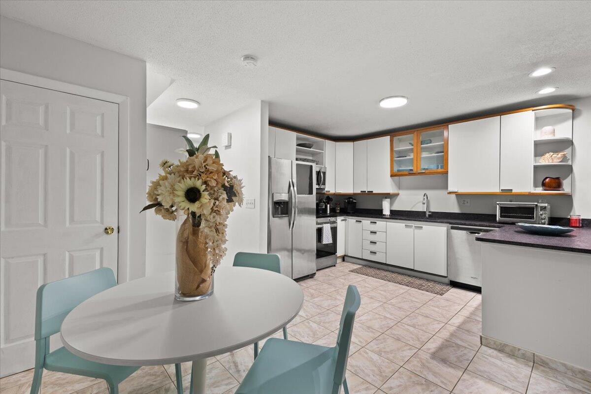 84 Round House Road Bourne, MA 02532 - Photo 16 of 35 a kitchen with stainless steel appliances kitchen island granite countertop a refrigerator a stove a sink dishwasher with a dining table and chair