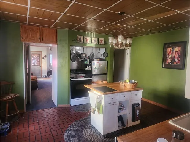 a utility room with stainless steel appliances kitchen island granite countertop a refrigerator and a sink