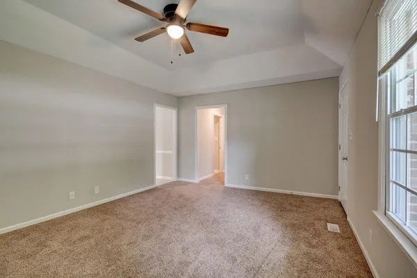 an empty room with windows and fan