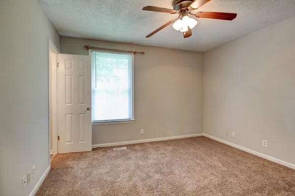an empty room with chandelier fan and windows