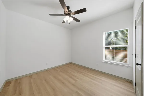 an empty room with a window and a ceiling fan