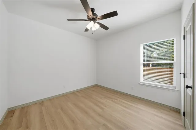 an empty room with a window and a ceiling fan