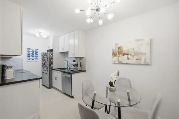 a kitchen with stainless steel appliances granite countertop a stove a refrigerator a sink a dining table and chairs with wooden floor