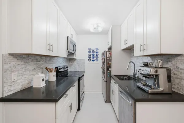 a kitchen with stainless steel appliances granite countertop a sink a stove and a refrigerator