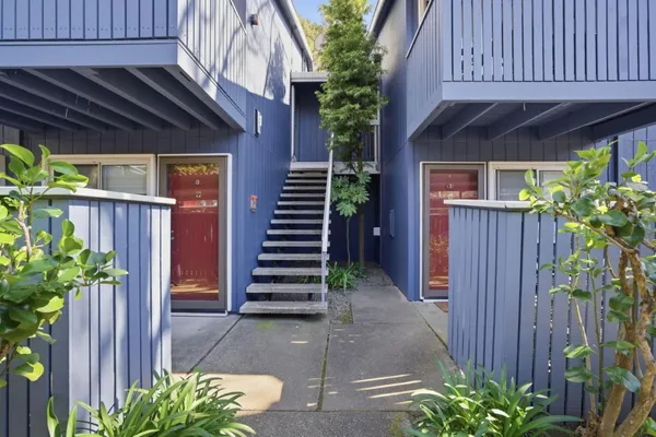 a backyard of a house with flower plants and wooden fence