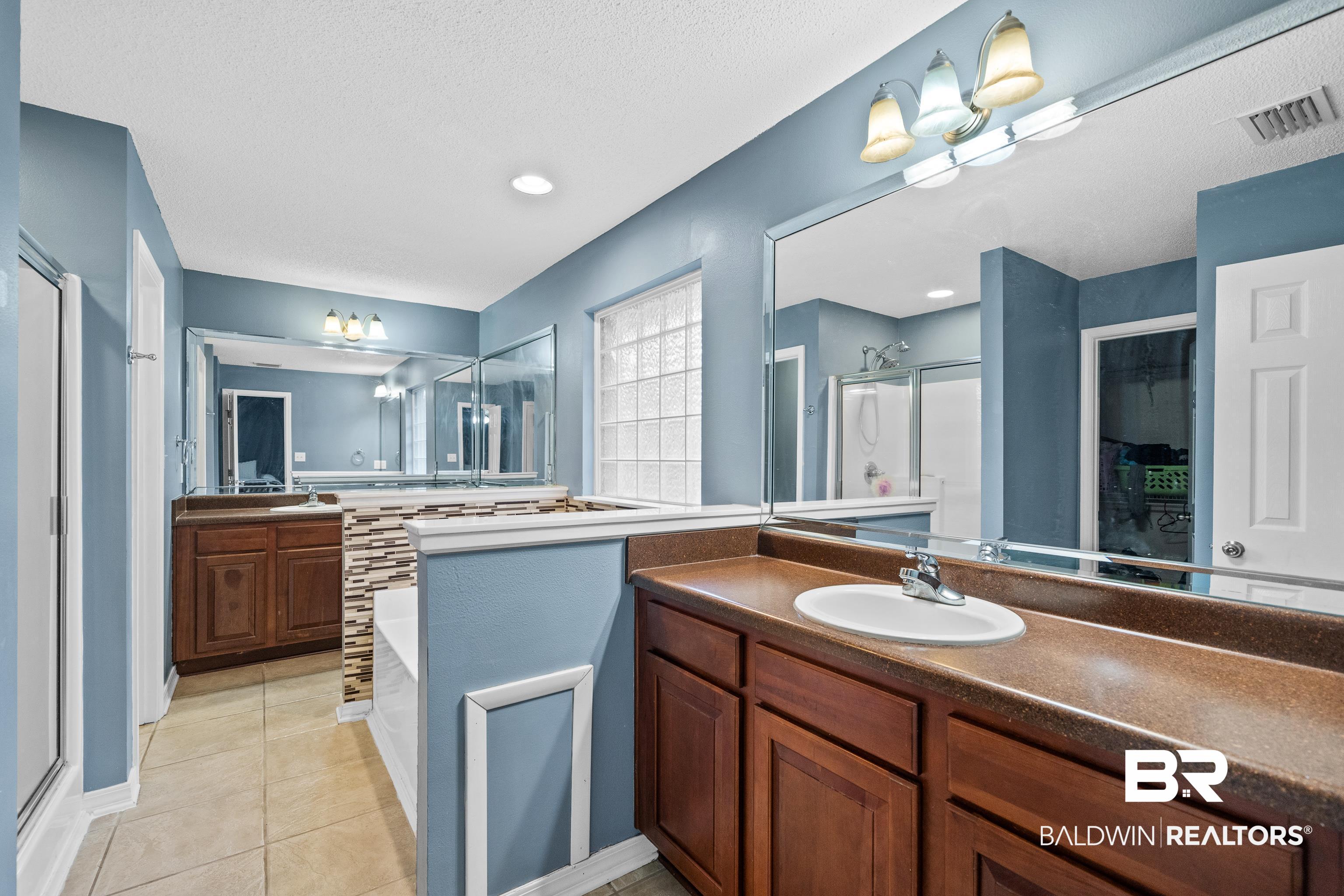 9552 Collier Loop Daphne, AL 36526 - Photo 17 of 28 Full bath featuring a shower stall, a bath, double vanities, tile patterned floors, and a textured ceiling
