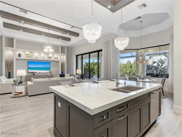 a kitchen with a stove a chandelier and a view of living room