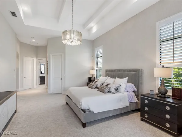 a spacious bedroom with a bed and a chandelier