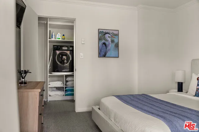 a bedroom with a bed and a washing machine with racks