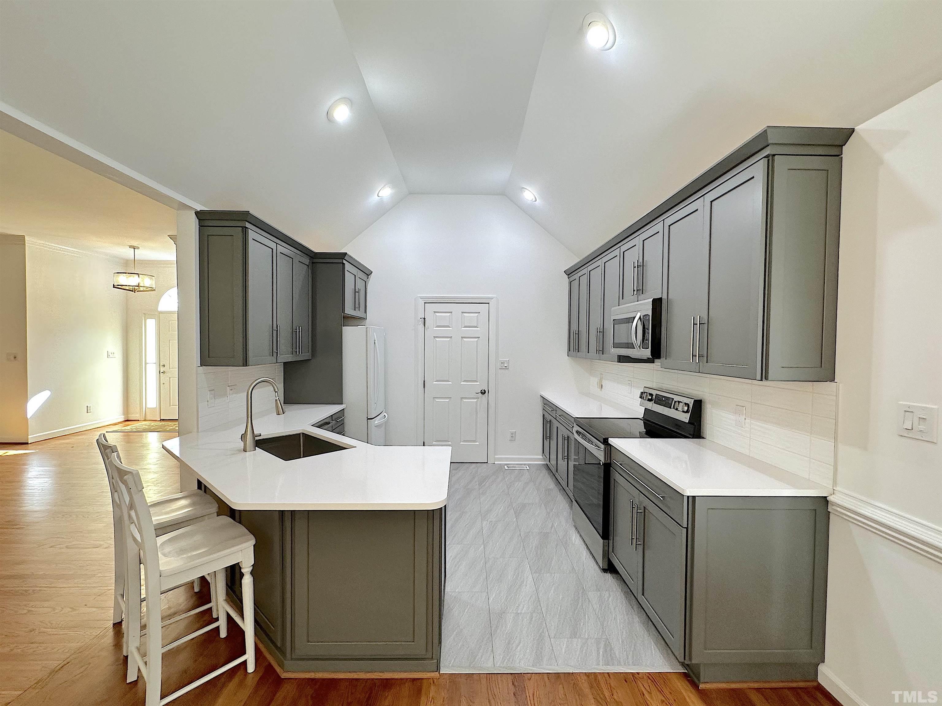 105 Wagon Trail Drive Cary, NC 27513 - Photo 7 of 22 a large kitchen with kitchen island a island a sink a stove and wooden floor