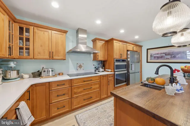 a kitchen with granite countertop a stove a sink dishwasher a dining table and chairs with wooden floor