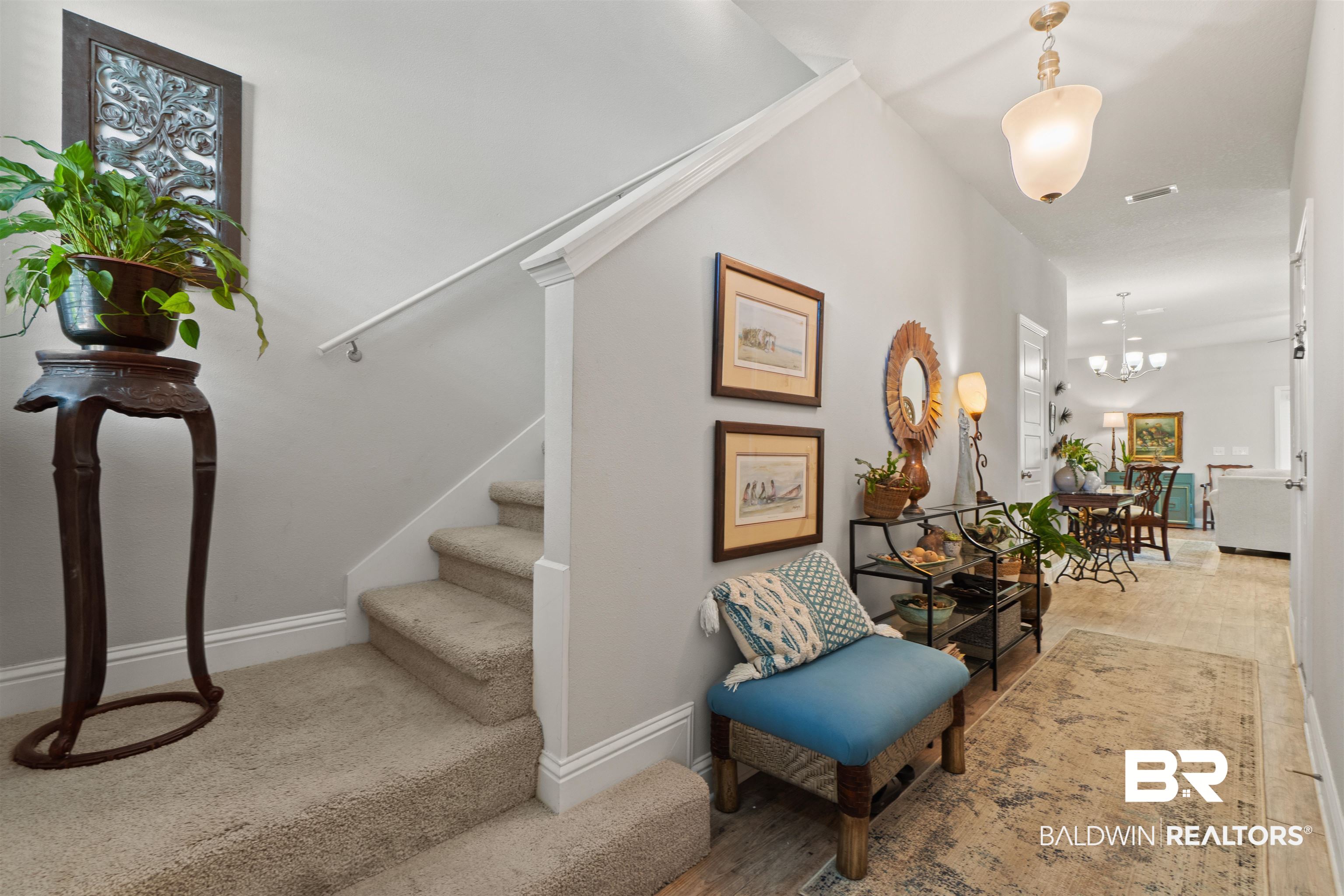 25806 Pollard Road, Unit 6 Daphne, AL 36526 - Photo 13 of 38 Carpeted staircase with white trim, leading to a bright hallway featuring wood-finish flooring and a pendant light fixture