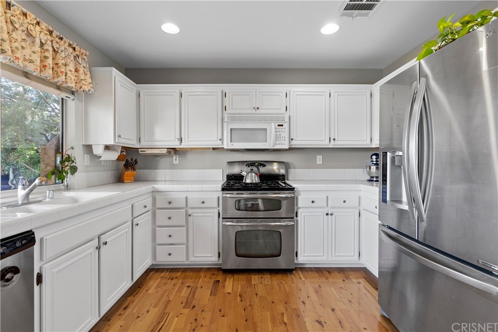 27710 Kristin Lane Saugus, CA 91350 - Photo 17 of 32 a kitchen with a refrigerator sink and white cabinets
