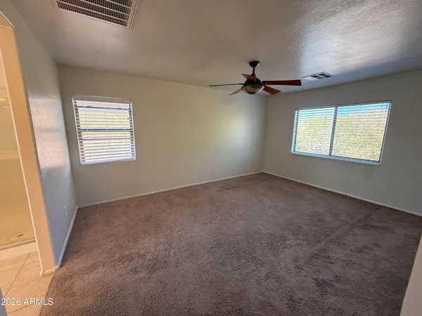 an empty room with windows and fan