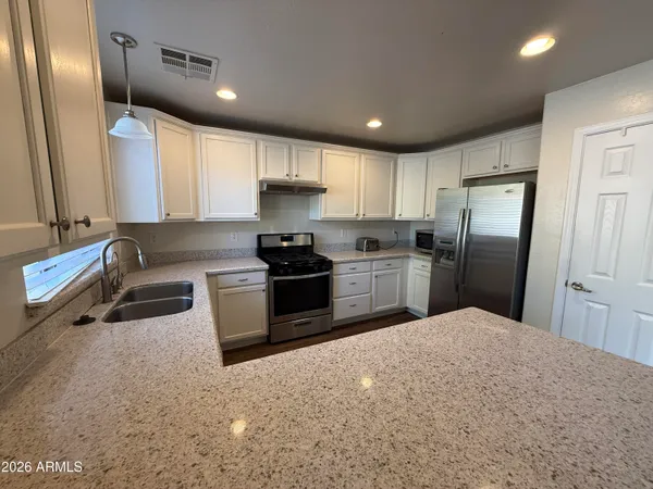 a kitchen with stainless steel appliances granite countertop a refrigerator sink and stove