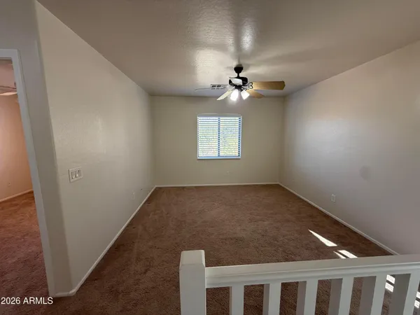 an empty room with windows and chandelier fan