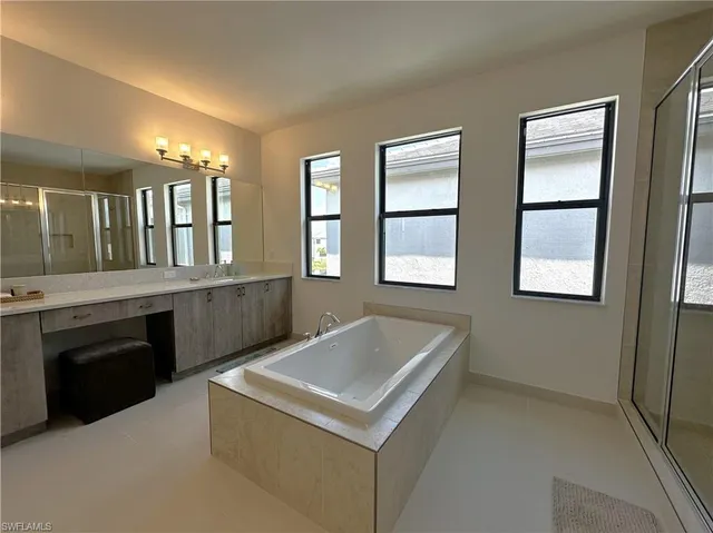 a spacious bathroom with a double vanity sink a mirror and a bathtub