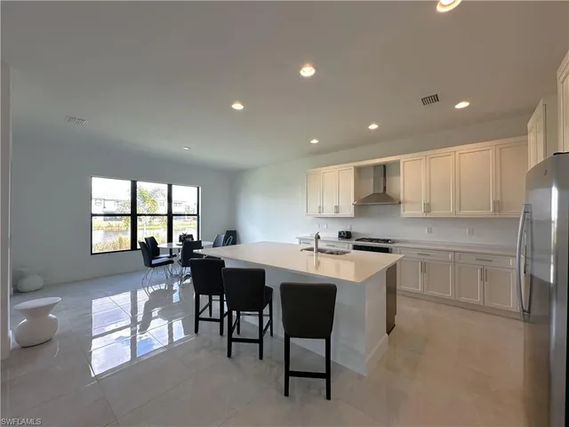 a kitchen with stainless steel appliances kitchen island granite countertop a sink a stove a dining table and chairs
