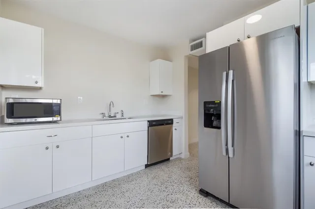 a kitchen with stainless steel appliances a refrigerator sink and white cabinets