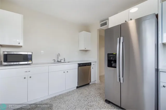 a kitchen with stainless steel appliances a refrigerator sink and white cabinets