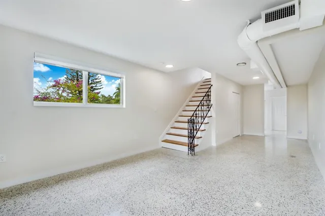 a view of an empty room with stairs and ventilation fan