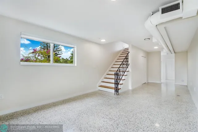 a view of an empty room with stairs and ventilation fan