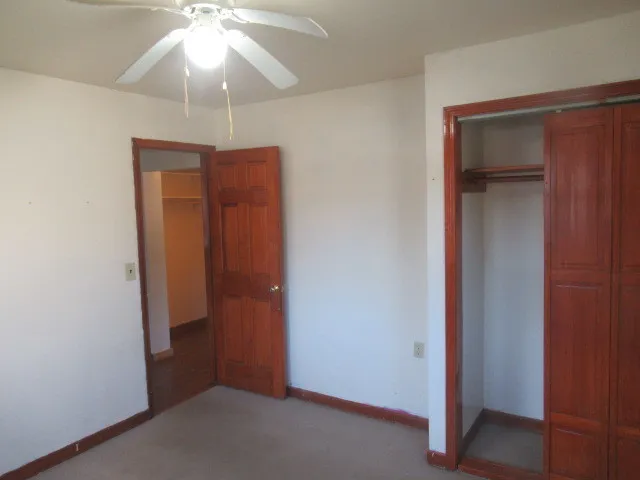 an empty room that has a fan and a fan