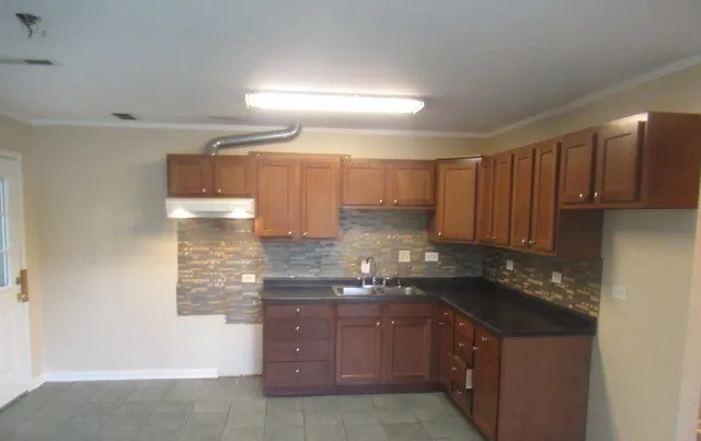 a kitchen with granite countertop a sink a stove and cabinets