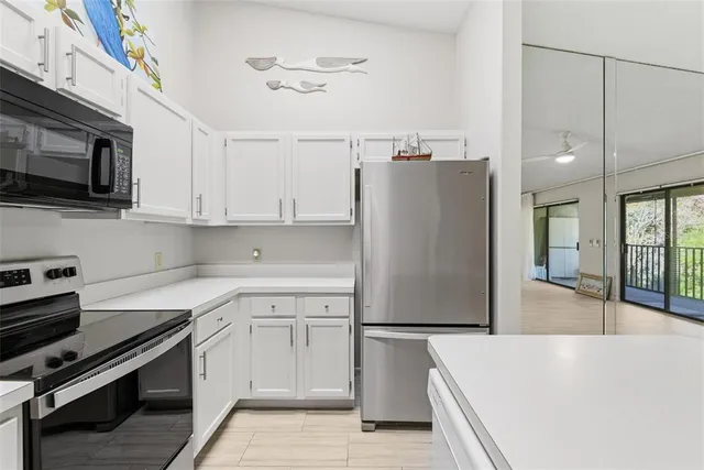 a kitchen with stainless steel appliances granite countertop a refrigerator a sink a stove and white cabinets with wooden floor