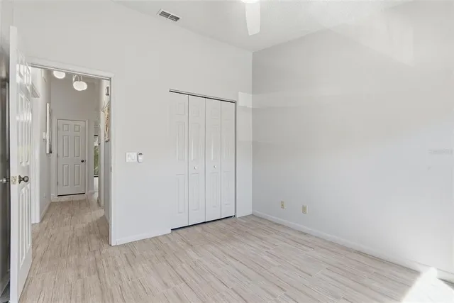 an empty room with wooden floor closet and windows