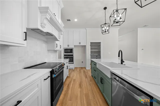 a kitchen with a sink dishwasher a stove top oven a clock and cabinets with wooden floor