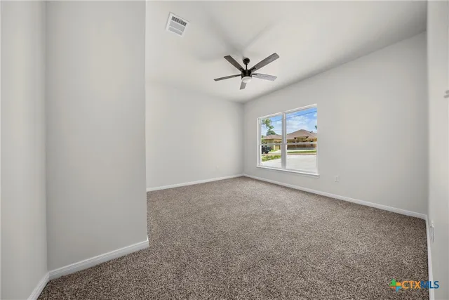 an empty room with a window and a ceiling fan