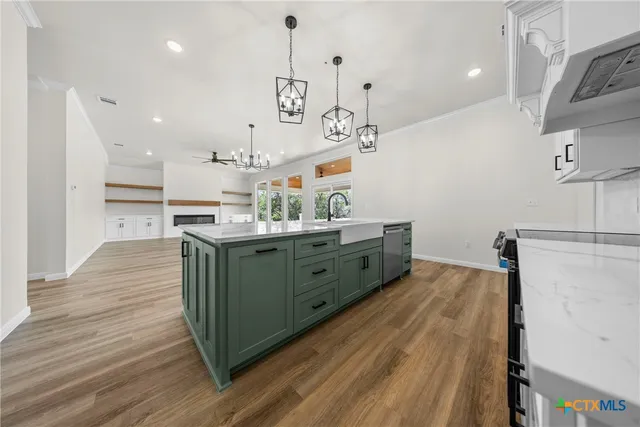 a kitchen with stainless steel appliances granite countertop a sink a stove and a wooden floors