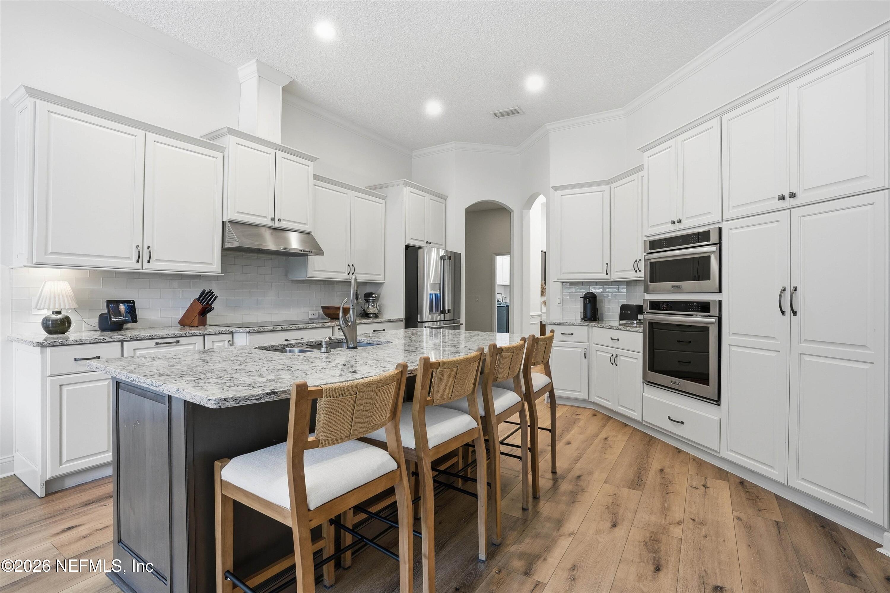 628 Pelham Road St. Augustine, FL 32092 - Photo 8 of 56 a kitchen with stainless steel appliances granite countertop a stove top oven a refrigerator a sink and white cabinets with wooden floor