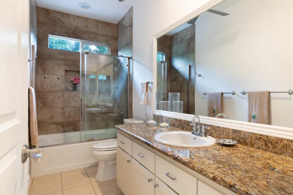 a bathroom with a granite countertop tub sink toilet and shower