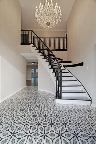 an empty room with wooden floor chandelier and windows