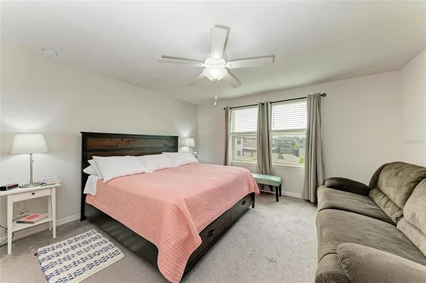 a bedroom with a bed lamp closet and three large window