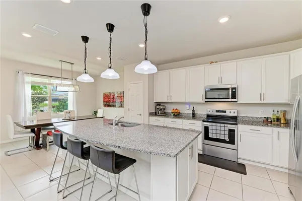 a kitchen with kitchen island granite countertop a stove a sink a dining table and chairs with wooden floor